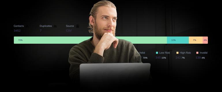 A smiling, thoughtful man working on a laptop. Email verification chart visible behind him.
